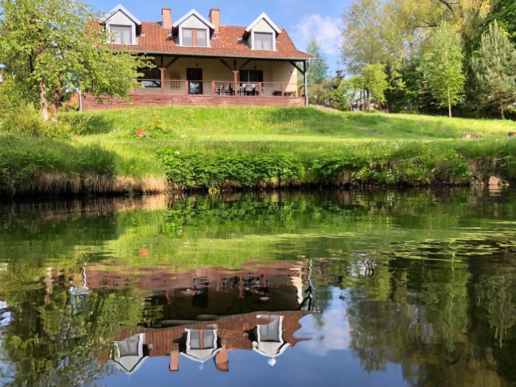 a house on a hill next to a river at Chalupa Dejnowo in Pilec