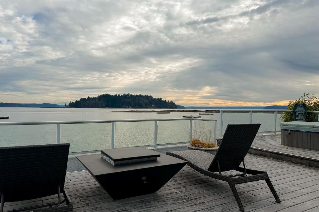 a balcony with a table and chairs and a view of the water at Shaws Cove Beachouse in Gig Harbor