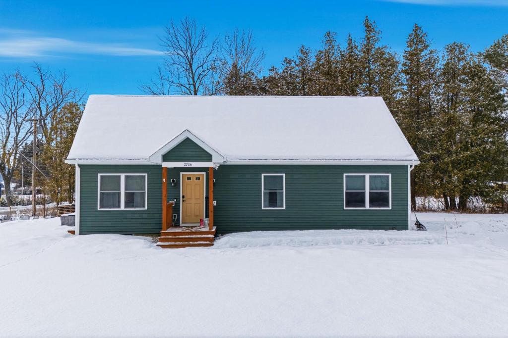 a green house with a snow covered roof at Schroon Lake Retreat in Schroon Lake