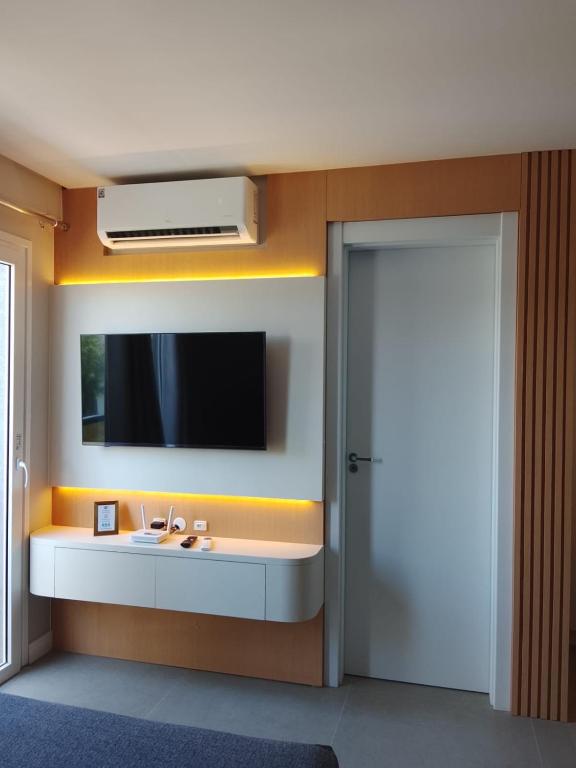 a bathroom with a sink and a tv on the wall at LINDO LOFT 350m Vila Germânica in Blumenau