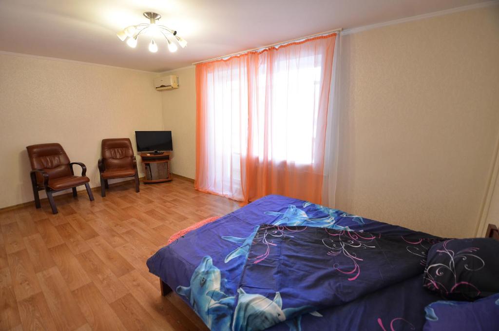 Schlafzimmer mit einem Bett, einem TV und einem Fenster in der Unterkunft Apartment on Navarynska in Mykolajiw