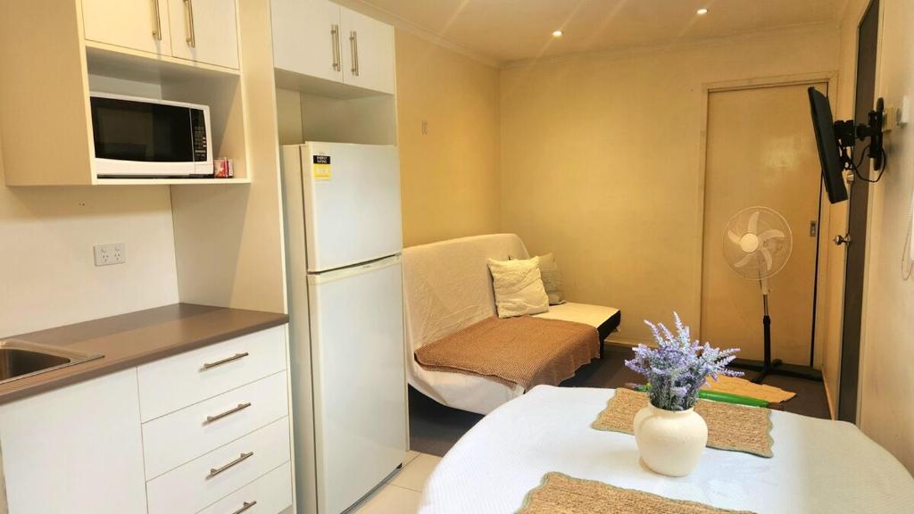a small kitchen with a refrigerator and a table at The Denman Lodge in Brisbane
