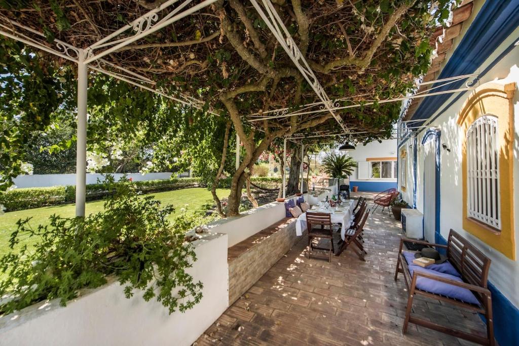 a patio with a table and chairs and trees at Family & Friends Retreat w/ Pool - Moncarapacho in Tavira