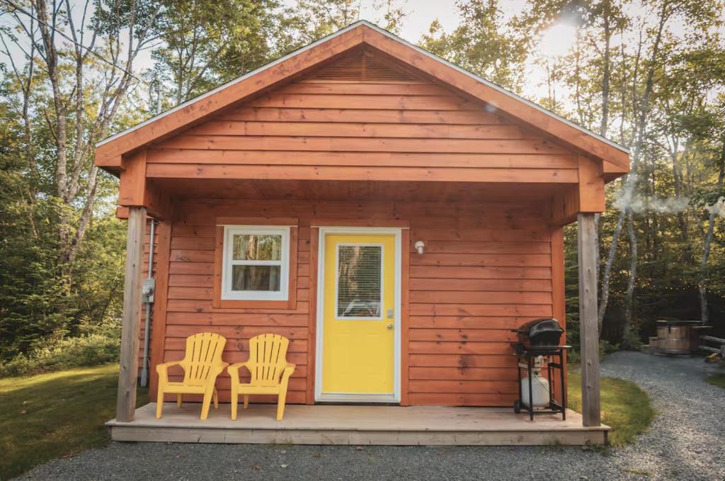 a cabin with two chairs and a yellow door at Lawrencetown Lodge - The Pine 2 Bed Room in Three Fathom Harbour