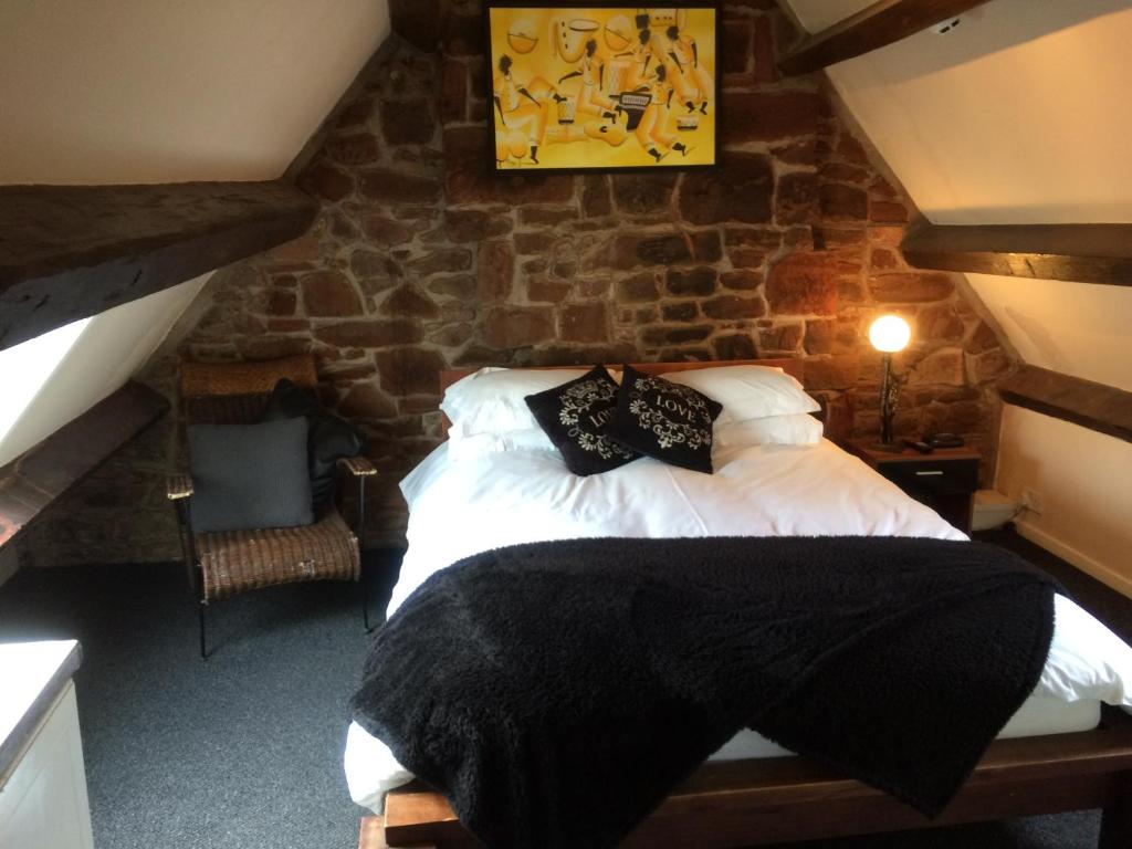 1 dormitorio con cama y pared de piedra en Lulus en St Bees
