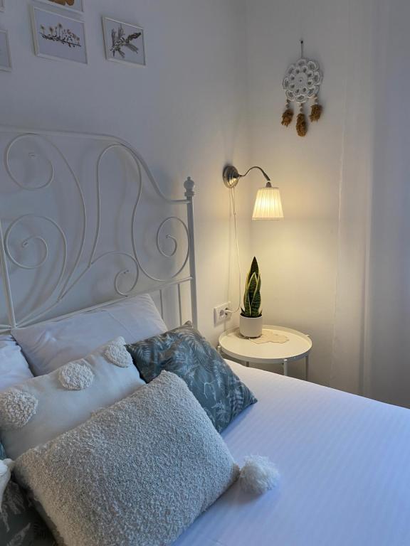 a bedroom with a white bed with two pillows and a lamp at Vikendica Fruška lipa in Čortanovci