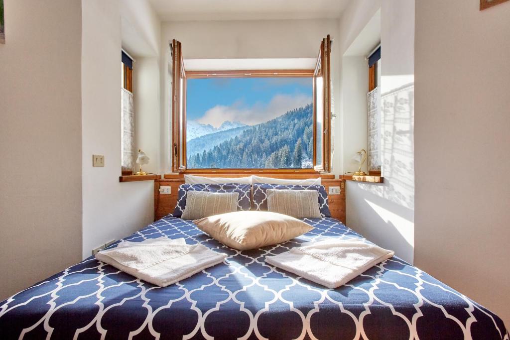 a bedroom with a bed with a large window at Dolomiti Comfortspace Free Parking in San Niccolò Comèlico
