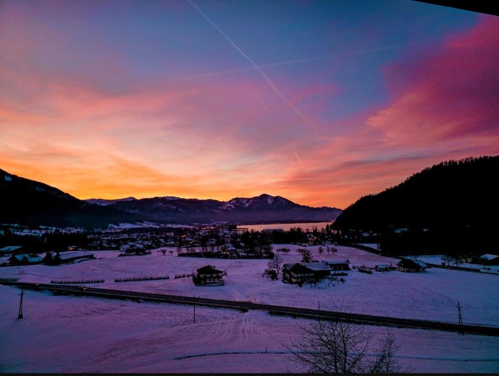 a sunset over a town with snow on the ground at Apartment Sunset am Wolfgangsee in Strobl