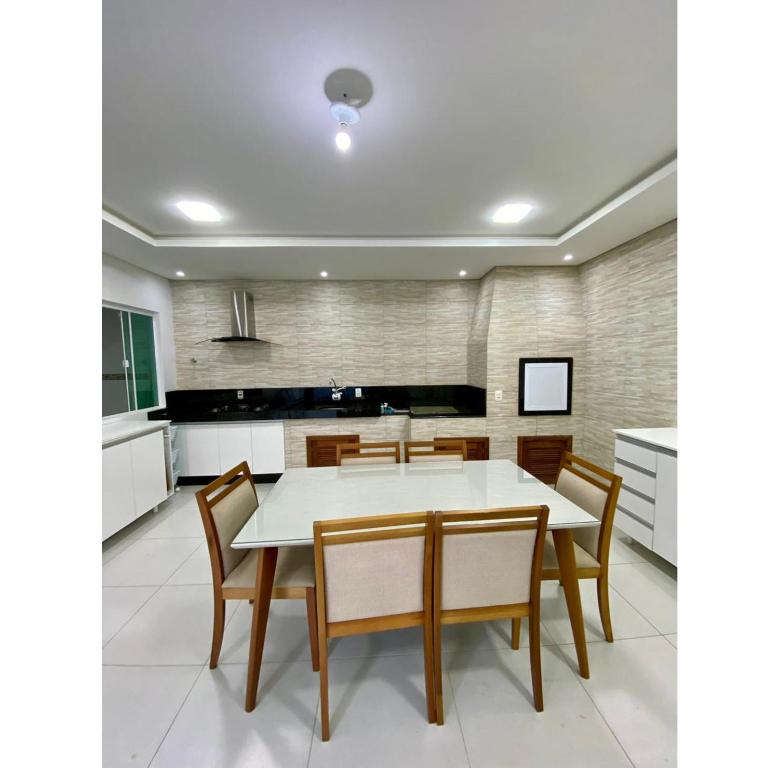 a kitchen with a white table and wooden chairs at Casa Aconchego Barra Velha/SC in Barra Velha