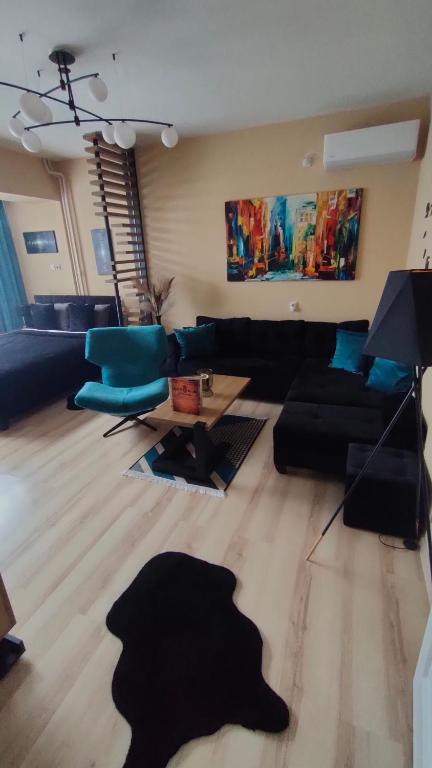ein Wohnzimmer mit einem schwarzen Sofa und blauen Stühlen in der Unterkunft Stan na dan Premium 030 in Bor