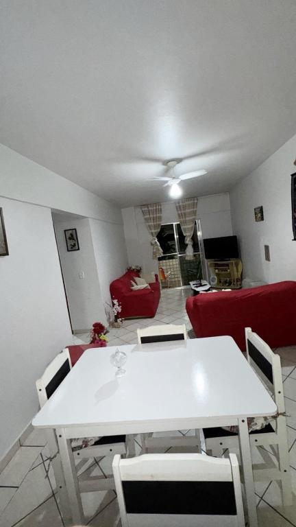 a living room with a white table and a red couch at Apartamento no centro de Mongaguá in Mongaguá