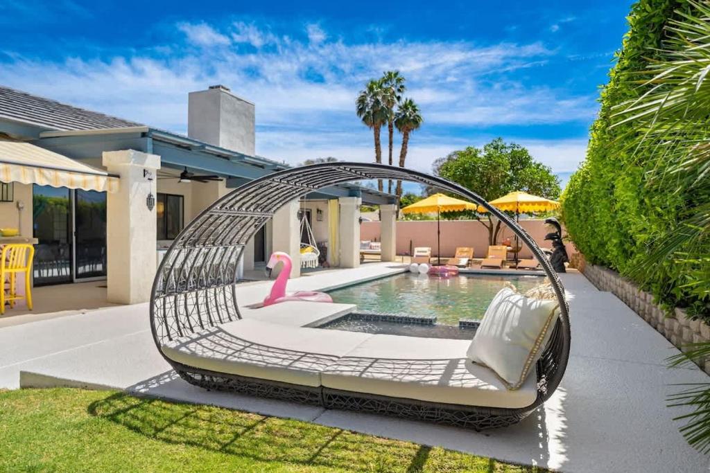 a metal swing with a pool in a backyard at Moroccan Desert Oasis -Salt Pool - Spa - Games in Bermuda Dunes