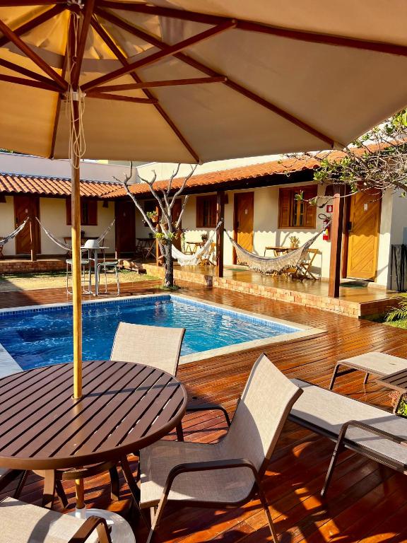 a pool with a table and chairs and an umbrella at Vila Bonita Guest House in Alto Paraíso de Goiás