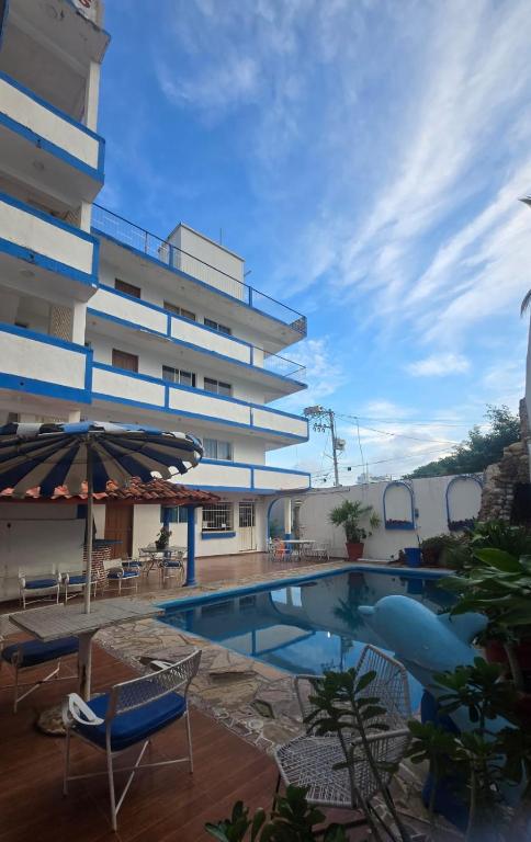 a hotel with a swimming pool in front of a building at Acapulco LUUM hotel in Acapulco