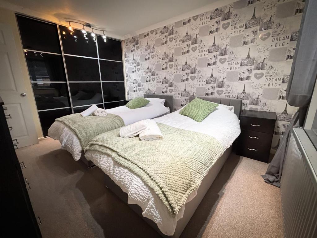 two beds in a bedroom with a wall of wallpaper at 6 Bed home near to Birmingham Nec Airport 6 miles from city centre in Marston Green