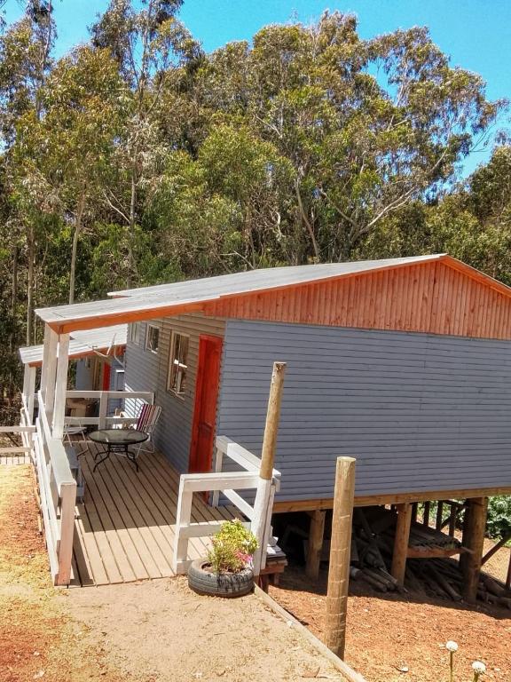 a small house with a wooden deck with a table at Cabañas Doña Magali in Bucalemu