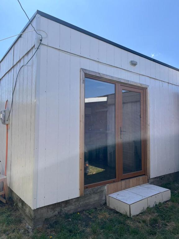 a small white building with a sliding glass door at Los Gladiolos in Melipeuco