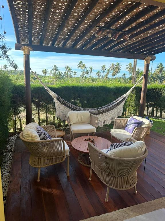 a hammock on a deck with chairs and a table at Apartamento Garden in Baixio