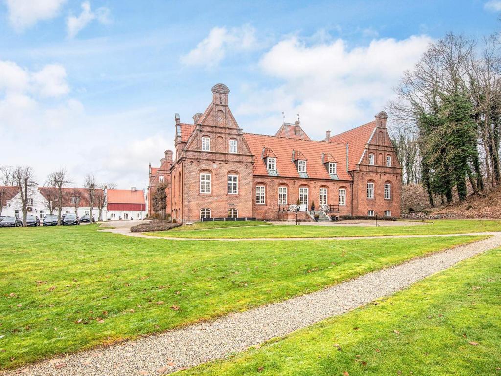 a large red brick building with a grass yard at Spacious holiday home with garden in Skanderborg