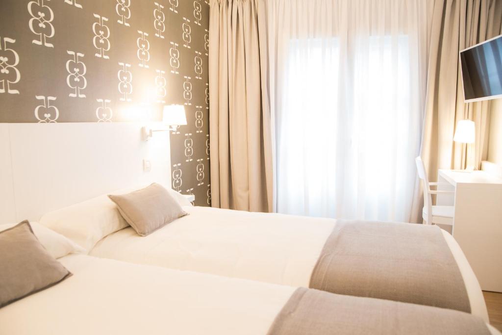 Una habitación de hotel con dos camas y una ventana. en Hostal Suso, en Santiago de Compostela