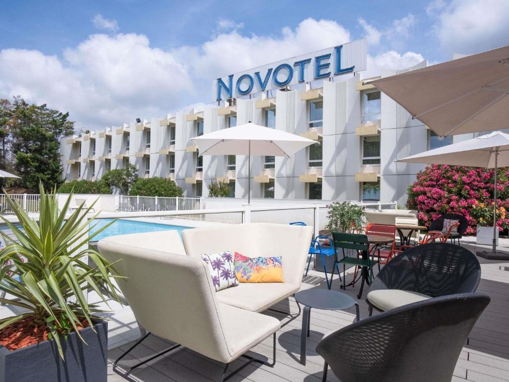 a hotel with chairs and tables in front of a pool at Novotel Narbonne Sud A9/A61 in Narbonne
