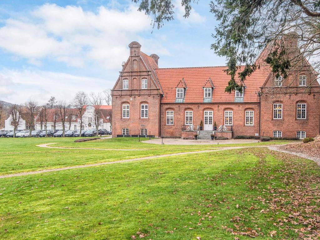 a large brick building with a grass field in front of it at 4 star holiday home in Skanderborg in Skanderborg