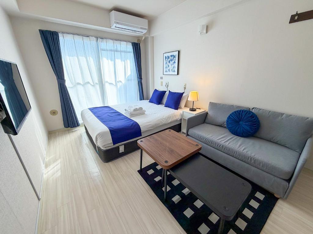 a hotel room with a bed and a couch at BALCOM STAY Hiroshima Takasu in Hiroshima
