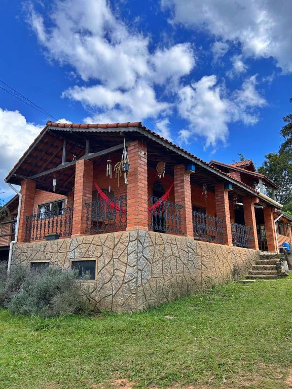 a large brick house with a stone wall at Pousada Chalés Vida Verde in Bom Jardim de Minas
