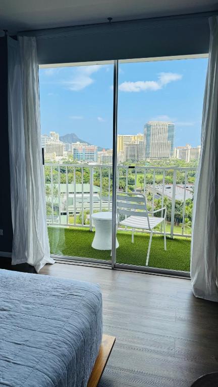 a bedroom with a large window with a view of the city at Inn on The Park in Honolulu