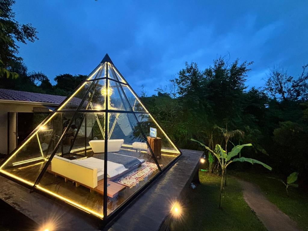 a glass house with a couch in a yard at Piramidevidro in Santa Isabel