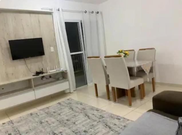 a living room with a table and chairs and a television at Apto mobiliado 7min da Orla de Atalaia e 1min do Aeroporto in Aracaju