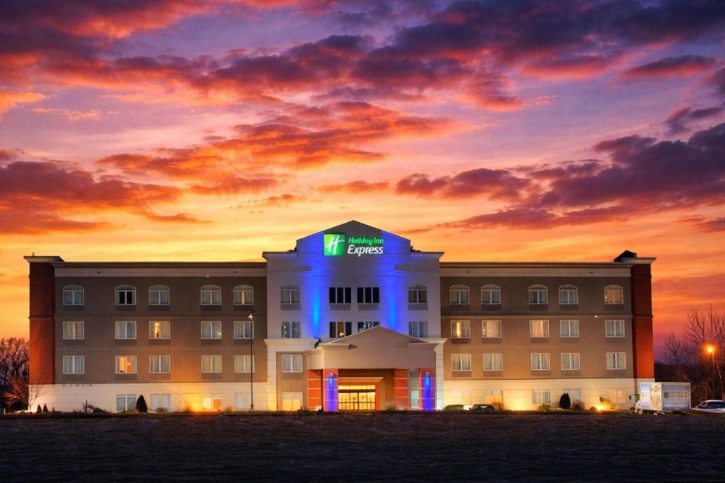 a hotel building with a lit up sign on it at Holiday Inn Express Syracuse-Fairgrounds by IHG in Warners