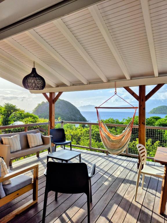a porch with a hammock and a view of the ocean at Villa Bois coco Les Saintes in Terre-de-Haut