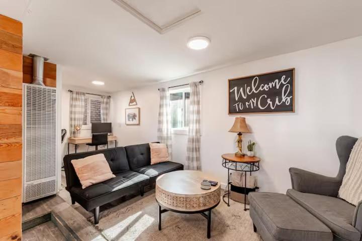 a living room with a black couch and a table at Brews, Bites, & Pines - Your downtown Flagstaff suite in Flagstaff