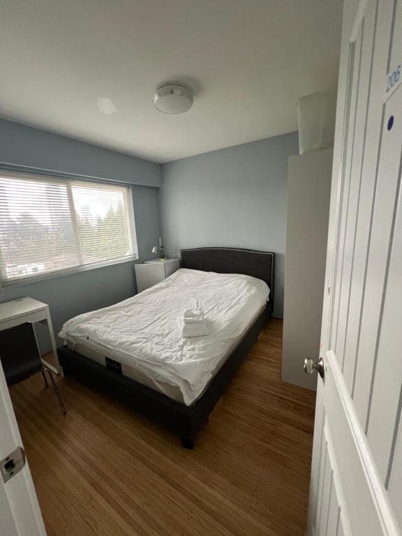 a small bedroom with a bed and a window at Brentwood Home in Burnaby