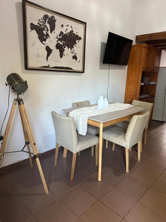 a dining room table with chairs and a world map on the wall at Alvear Centro Hospedaje in General Alvear