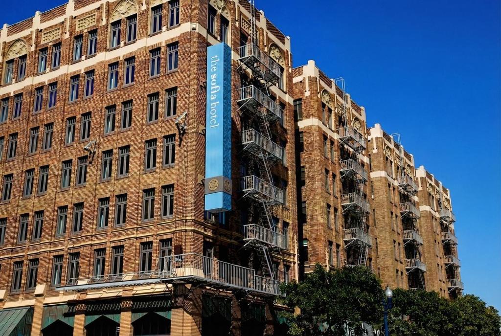a tall brick building with a blue sign on it at The Sofia Hotel in San Diego