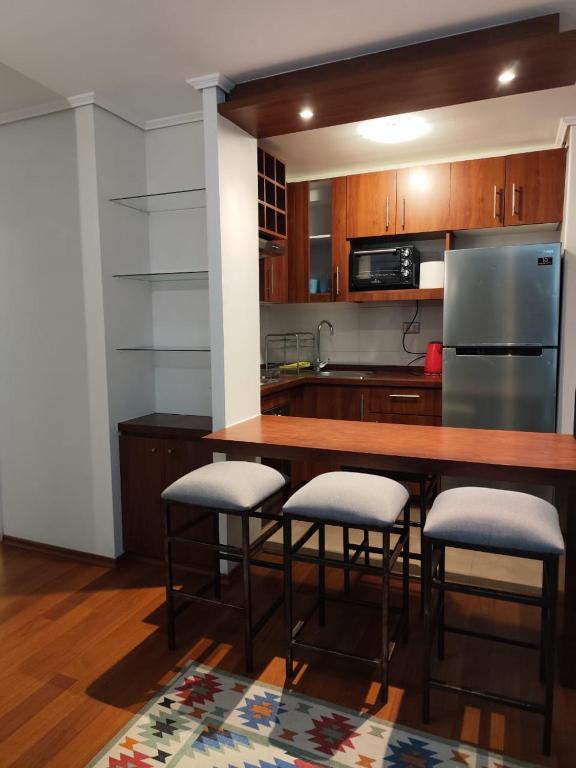 a kitchen with a bar with stools and a refrigerator at Valparaiso01 in Valparaíso