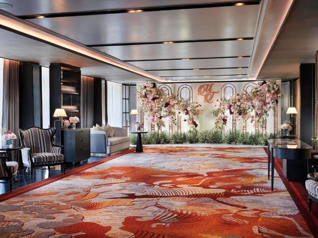 A spacious event-ready lobby with patterned carpet, lounge chairs, and a floral backdrop.