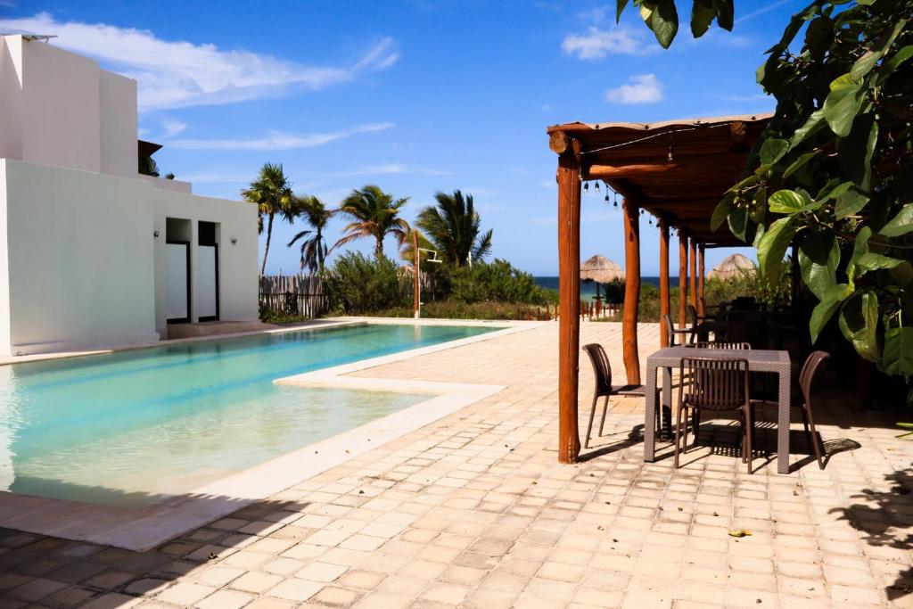 a swimming pool with a table and chairs next to a building at Club de Playa Sóol in Telchac Puerto