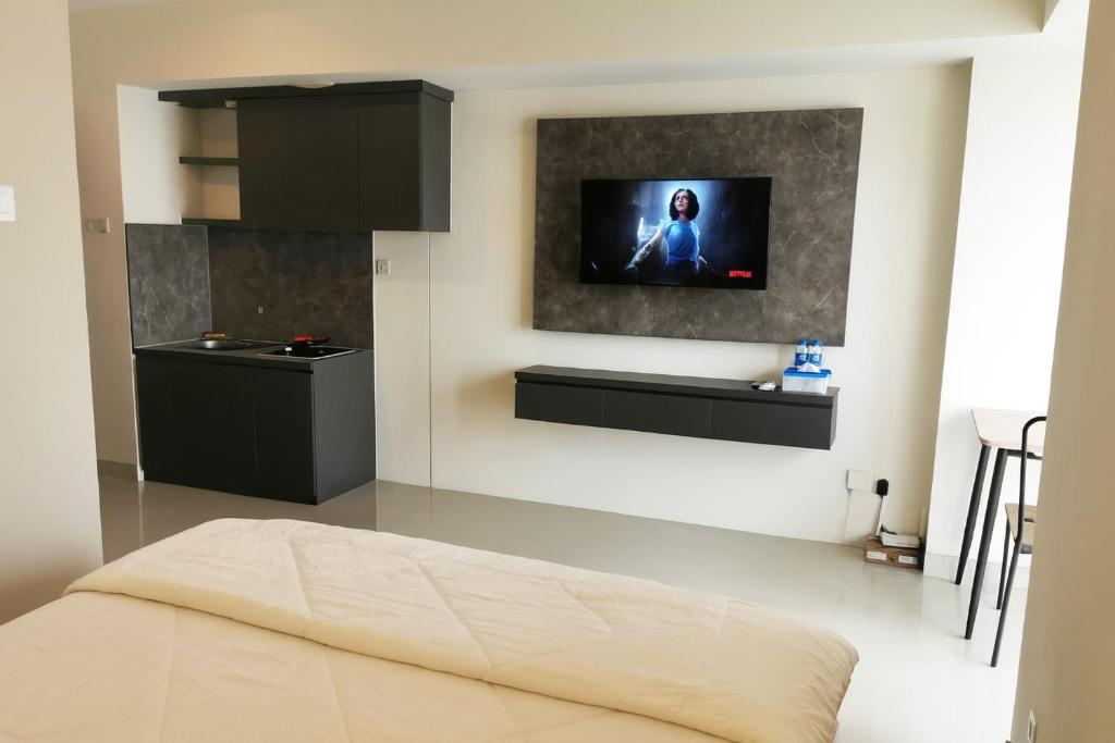 a bedroom with a bed and a tv on the wall at Grand Kamala Lagoon by Whitebox in Bekasi
