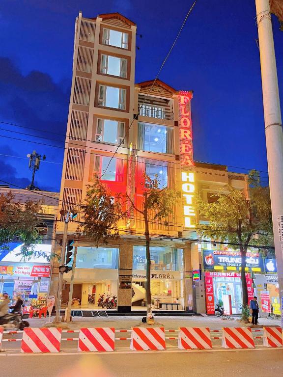 a tall building with neon signs in front of it at Khách Sạn FLORÉA in Phan Rang–Tháp Chàm