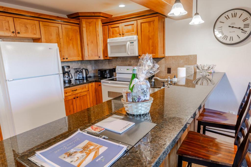 a kitchen with a white refrigerator and wooden cabinets at Snowmass 2br Getaway Pool, Hot Tub & Ski Access - D2 in Snowmass Village