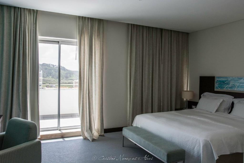 a hotel room with a bed and a large window at Hotel Praia in Nazaré