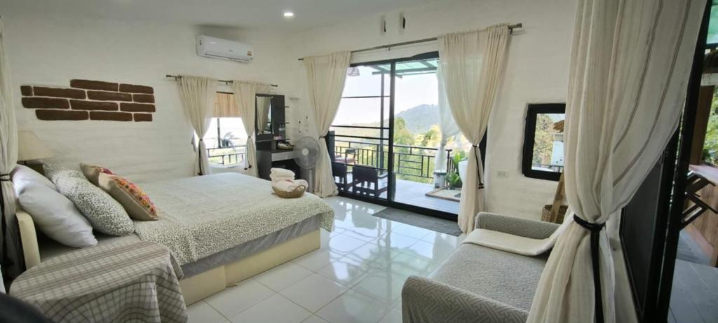 a bedroom with a bed and a couch and a balcony at ตั้วบ้านดิน Tuabaandin in Ban Thung Phan Ha
