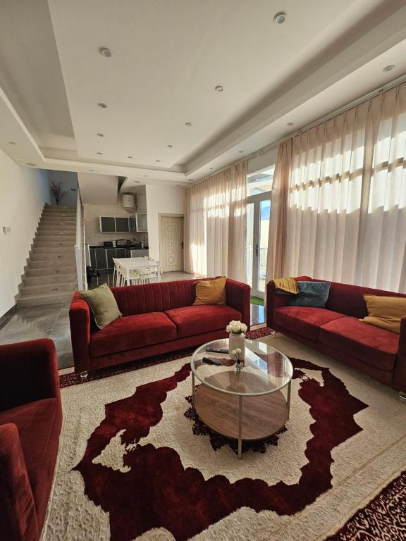 a living room with red couches and a coffee table at TiDise Villas & Chalets إستراحة وشاليه تايدايس in Bimmah