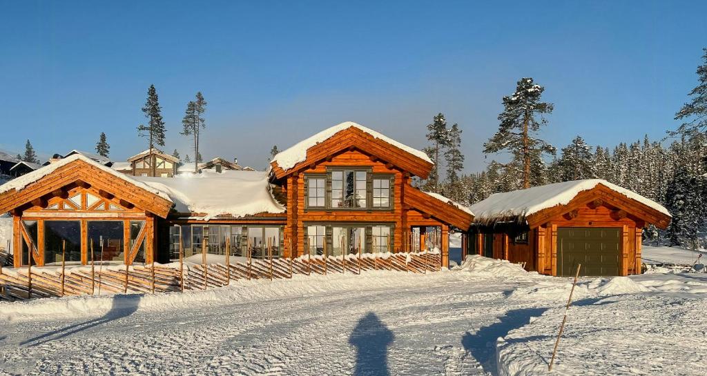 a log cabin with snow on the roof in the snow at Log Cabin With Views Over Turufjell in Flå
