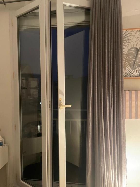a glass door in a room with a curtain at Albar Rooftop Eiffel Paris Porte de Versailles in Issy-les-Moulineaux