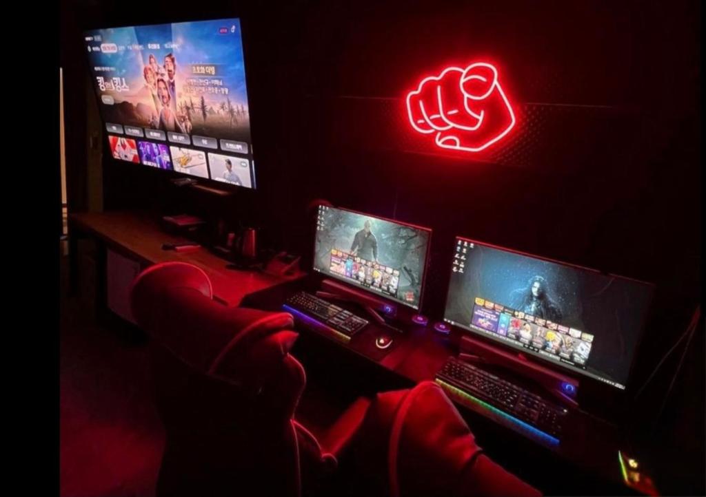 a room with three computer monitors and a neon sign at 달빛소리호텔 in Ajung-yŏk