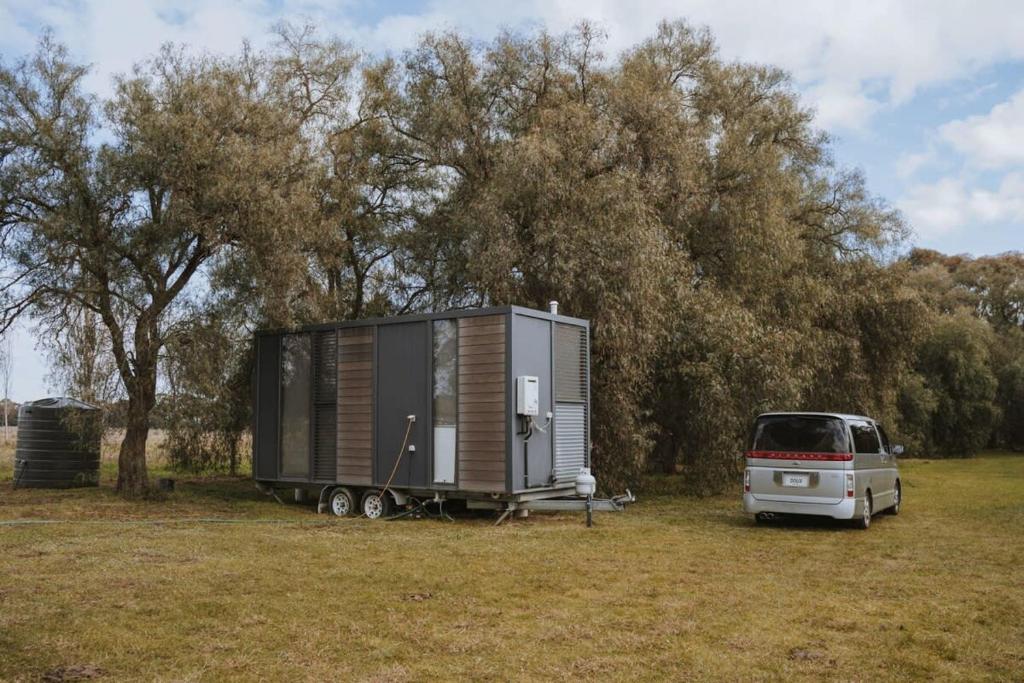 a van parked in a field with a tiny house at Organic Farm Stay by Tiny Away in Numurkah